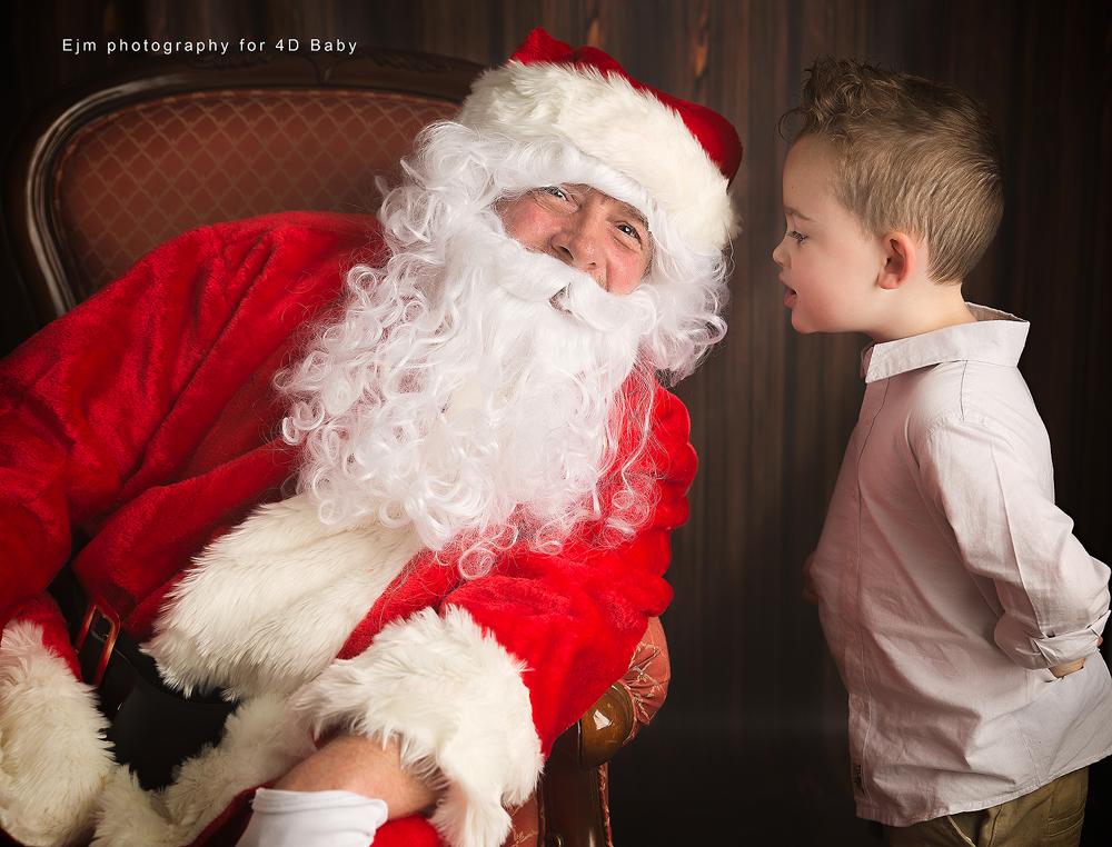 little boy whispering to santa what he wants for christmas in a photoshoot