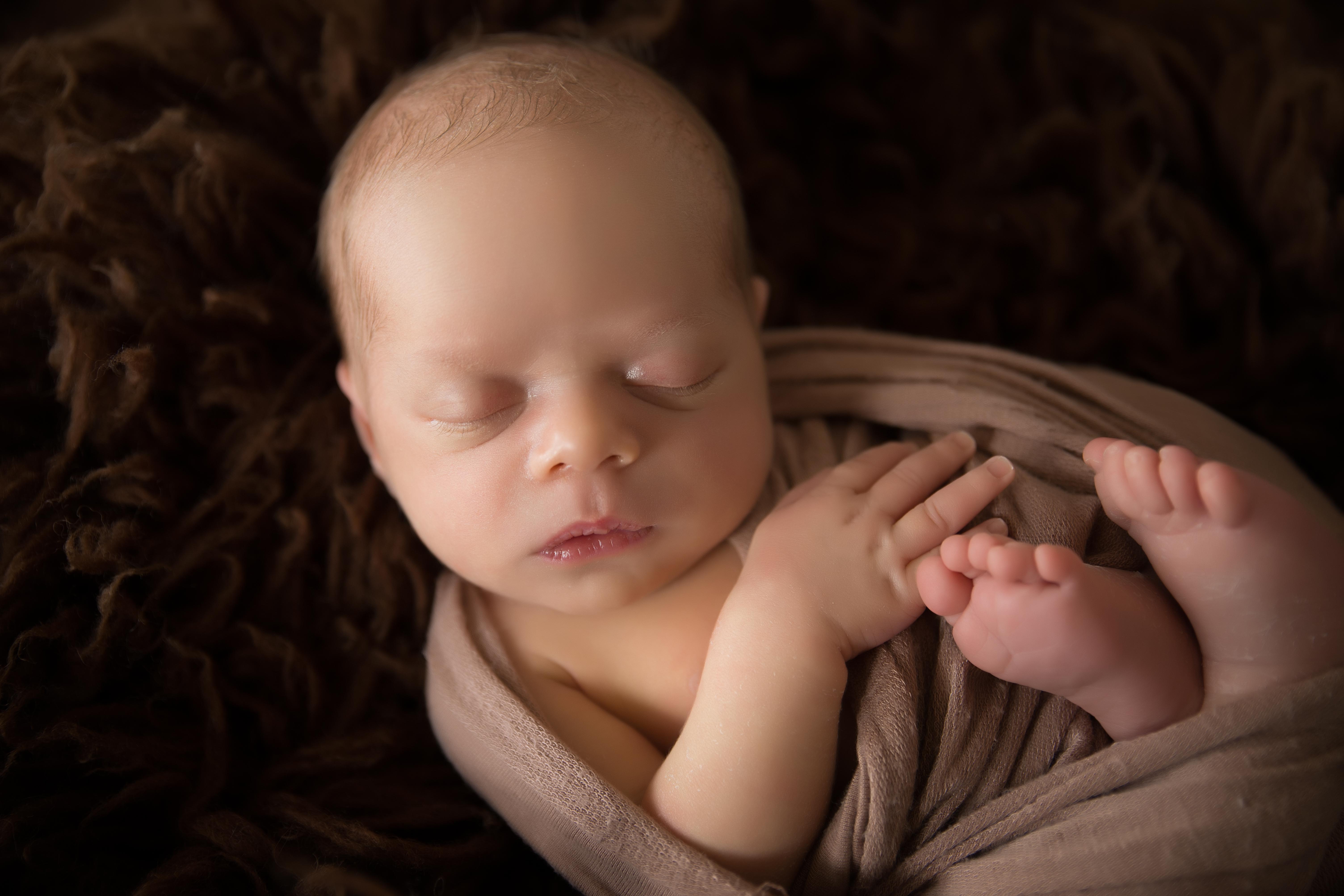 newborn baby wrapped in a brown wrap 