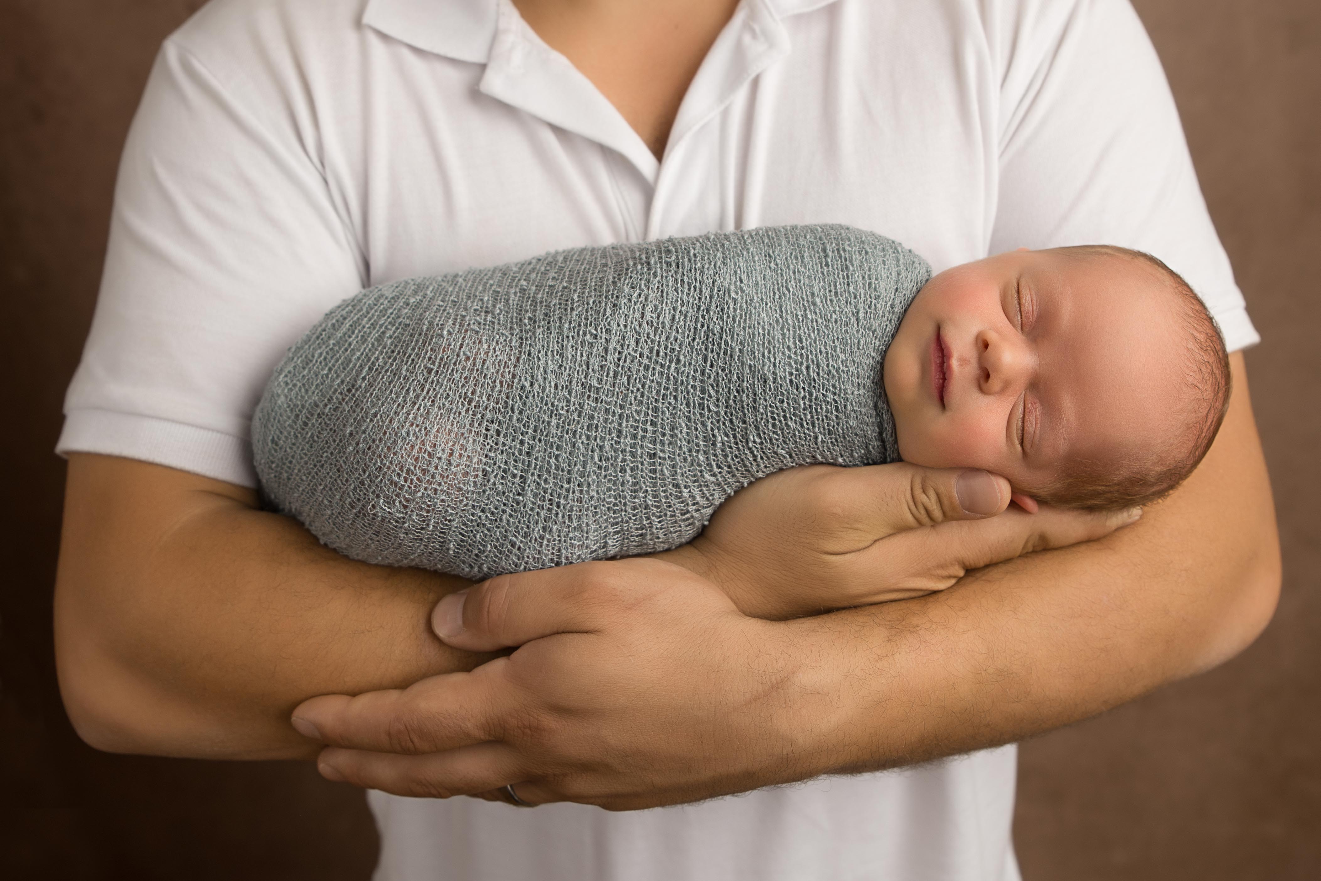 Newborn laying in dads arms 