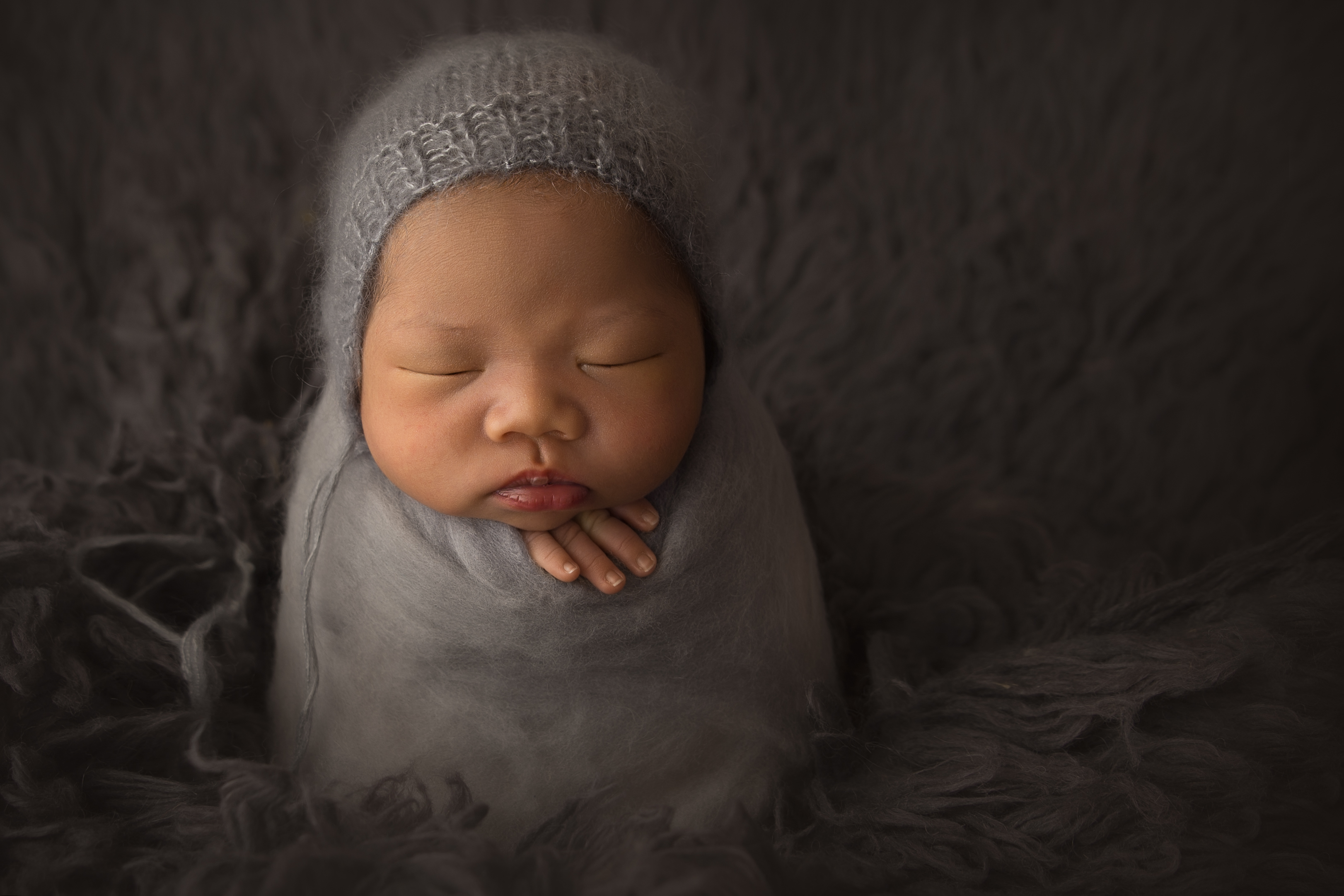 Newborn baby upright with little hand out for newborn photography 