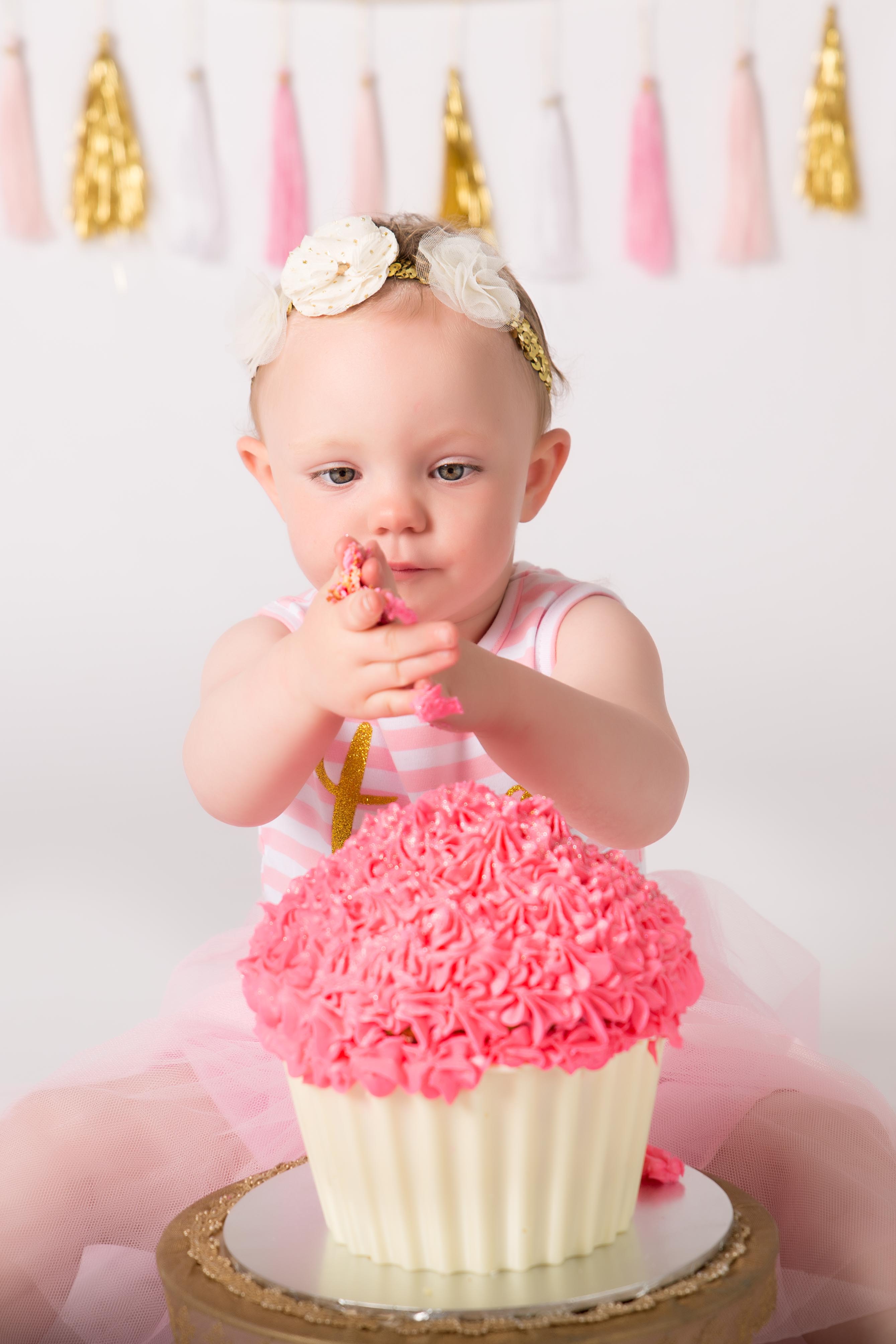 one year old digging into huge cupcake