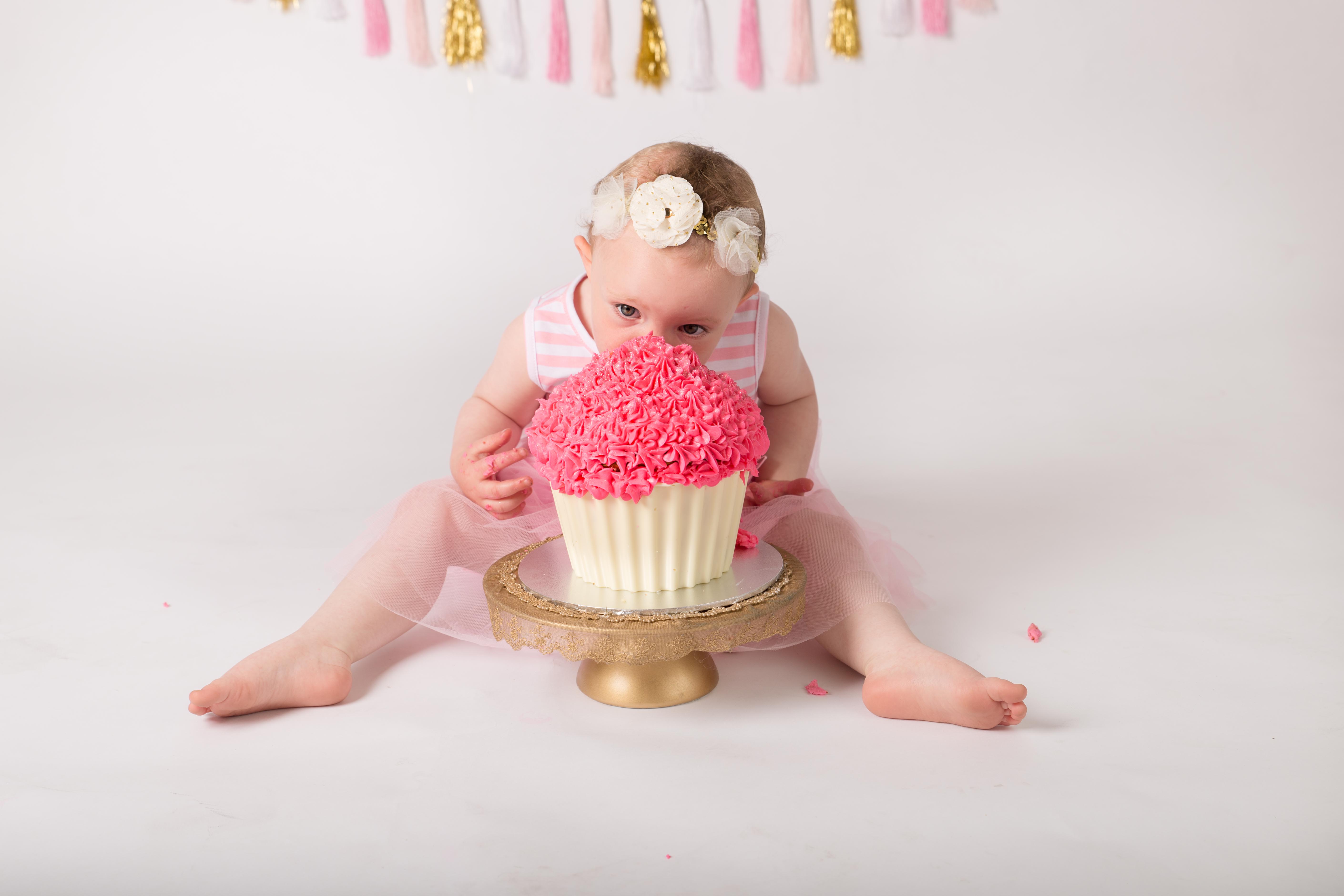 One year old taking massive bite of cake for photo shoot