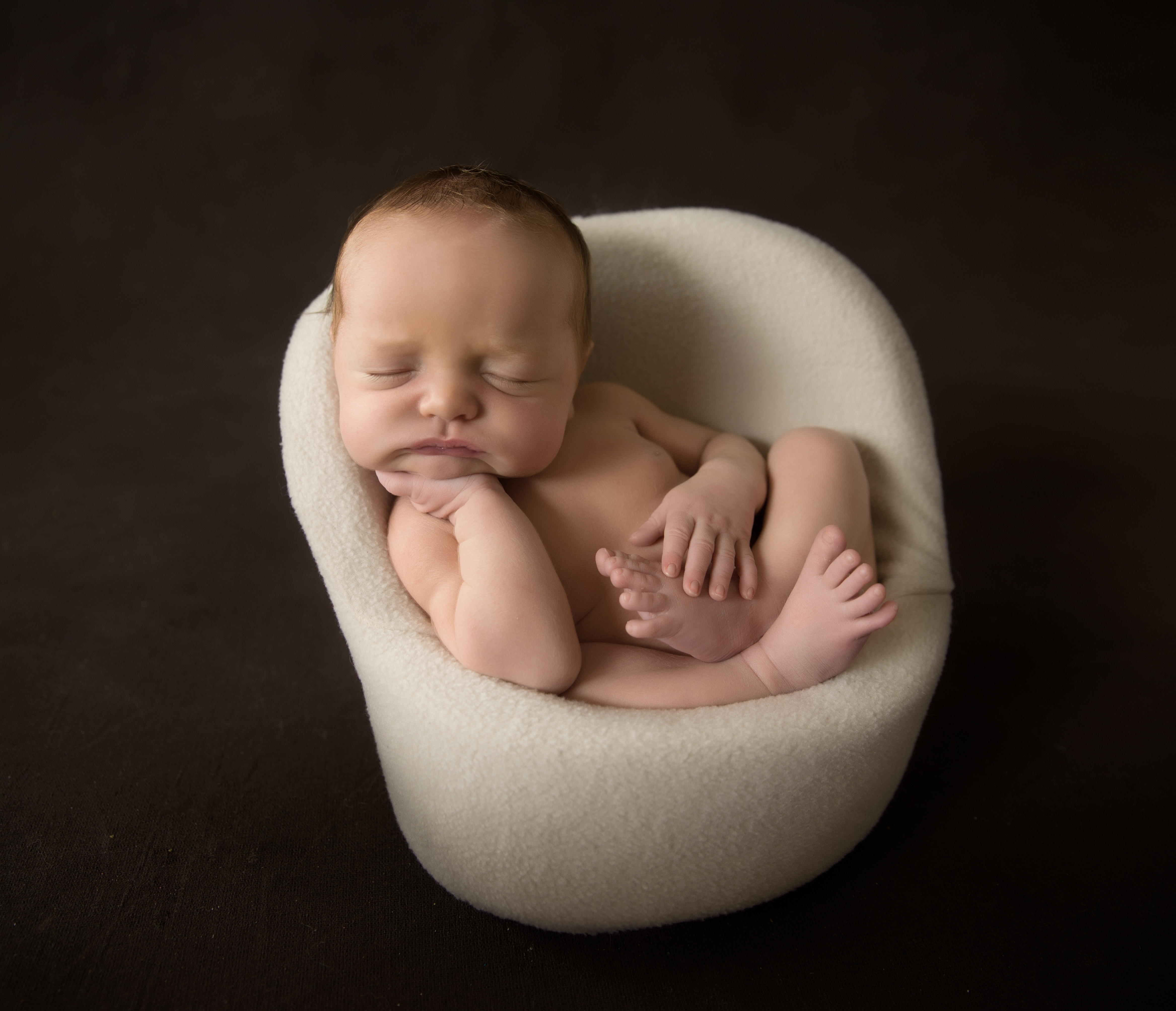 Newborn baby posed in little chair for photography 