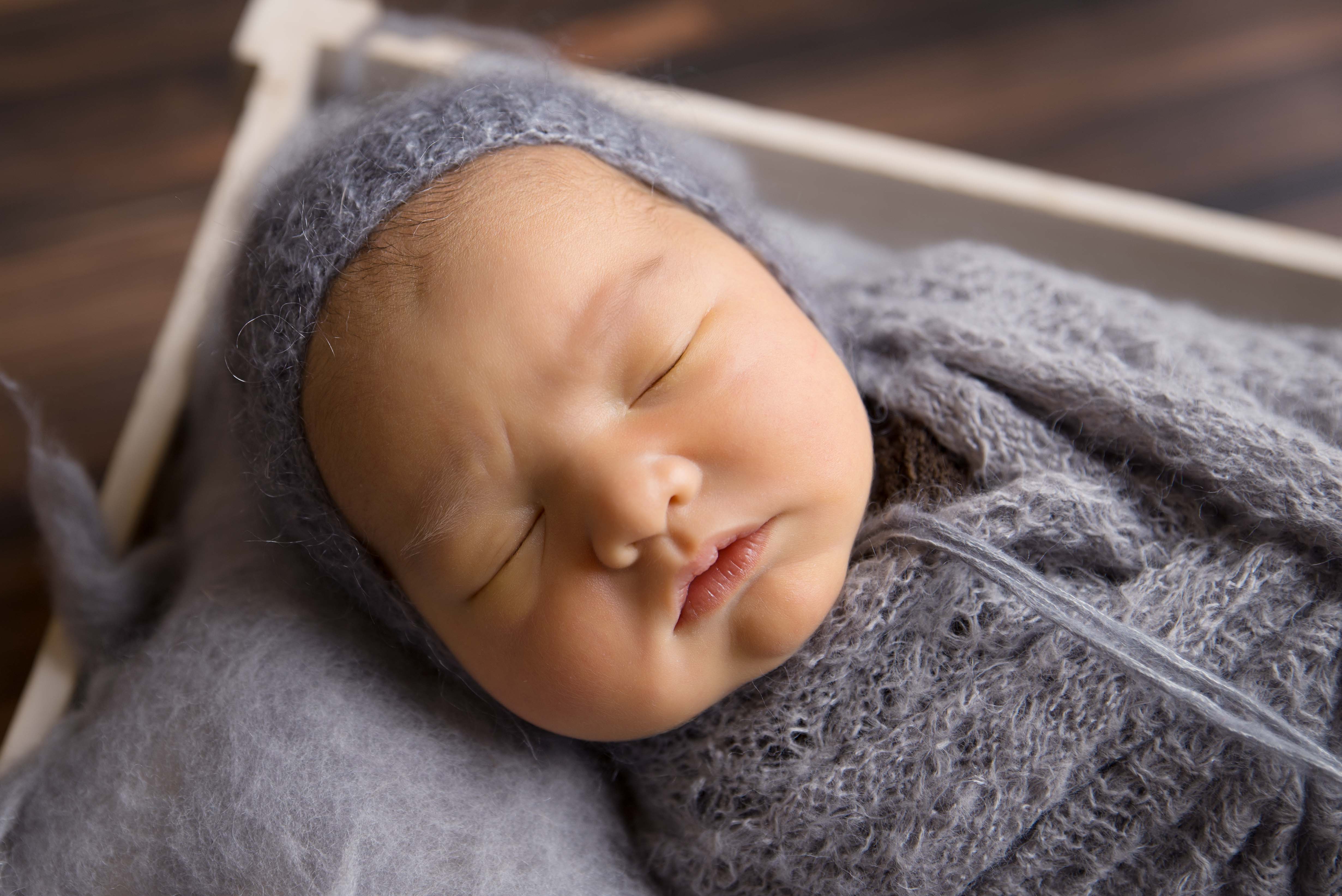 Newborn baby in grey bonnet. 