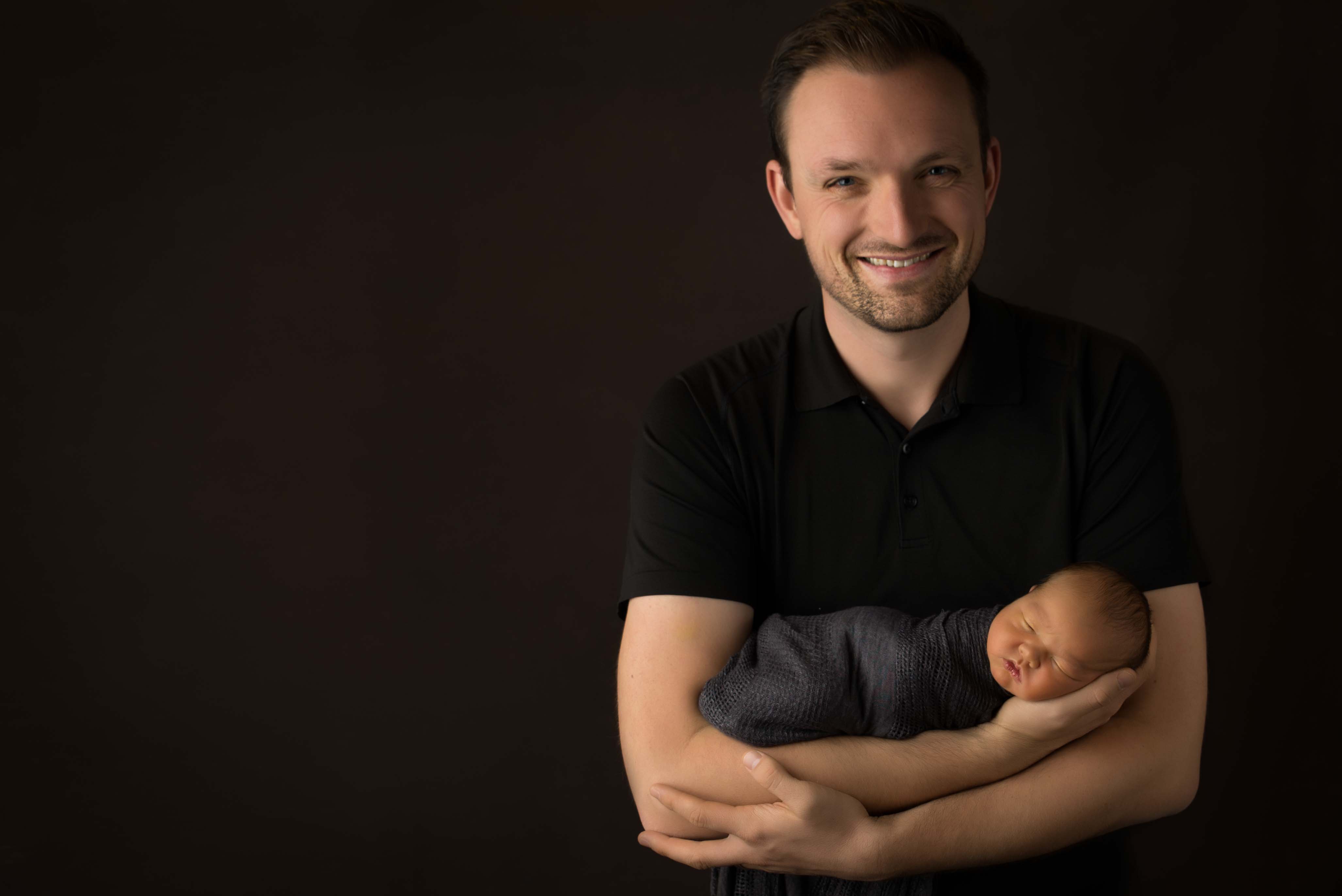 Dad holding baby for newborn photograph. 