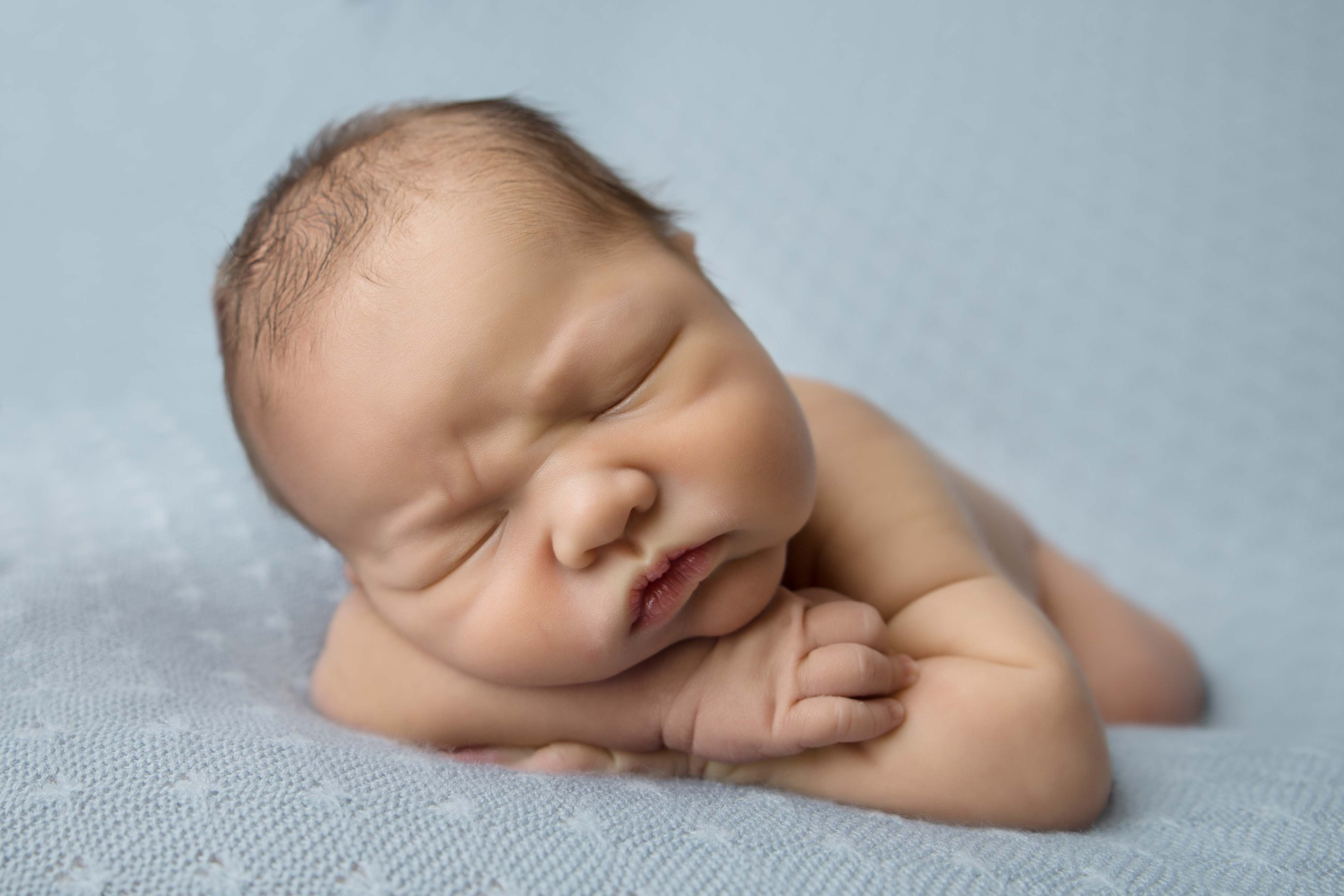 Newborn baby with head on arm for photography.