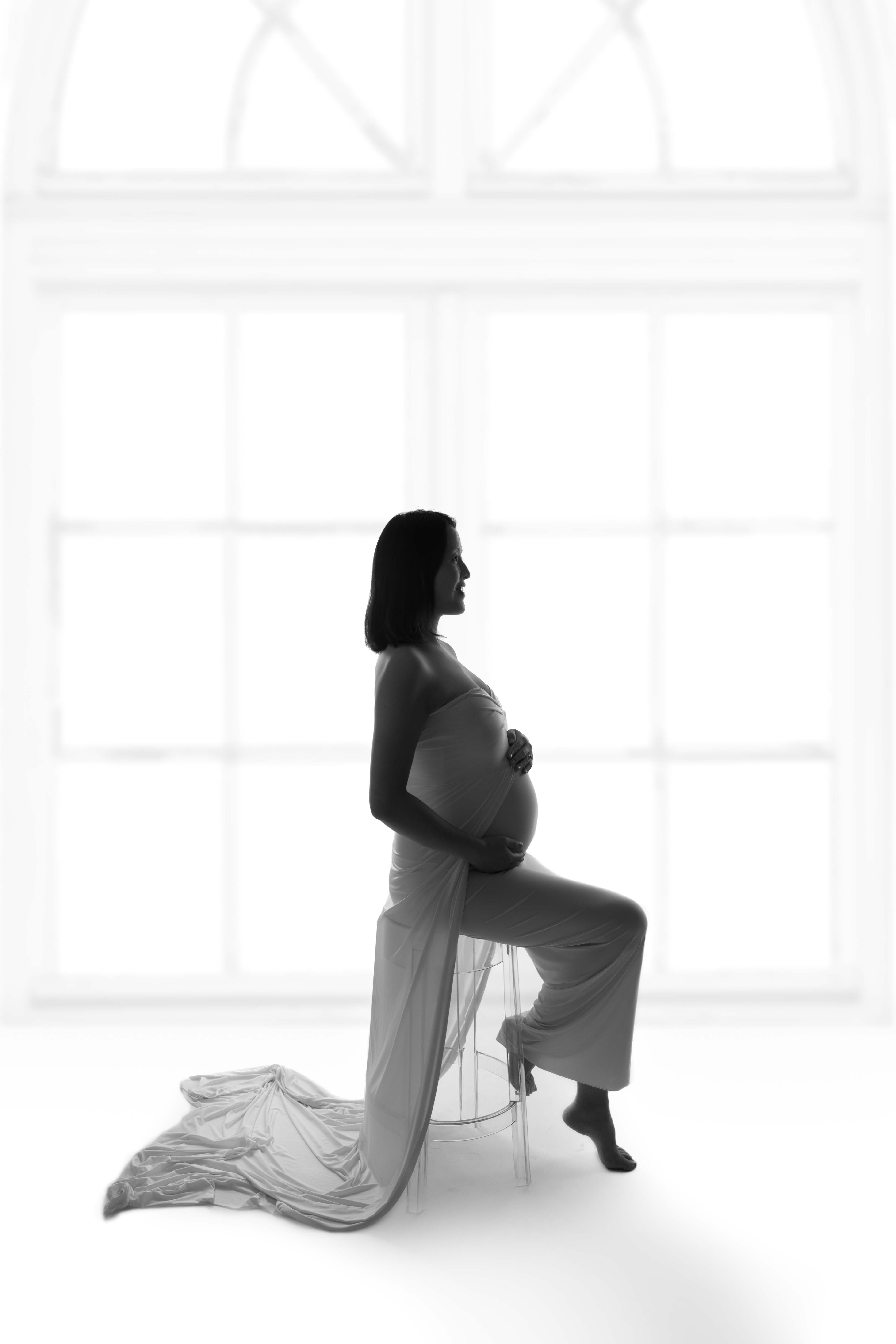 Maternity image on stool infant of window.