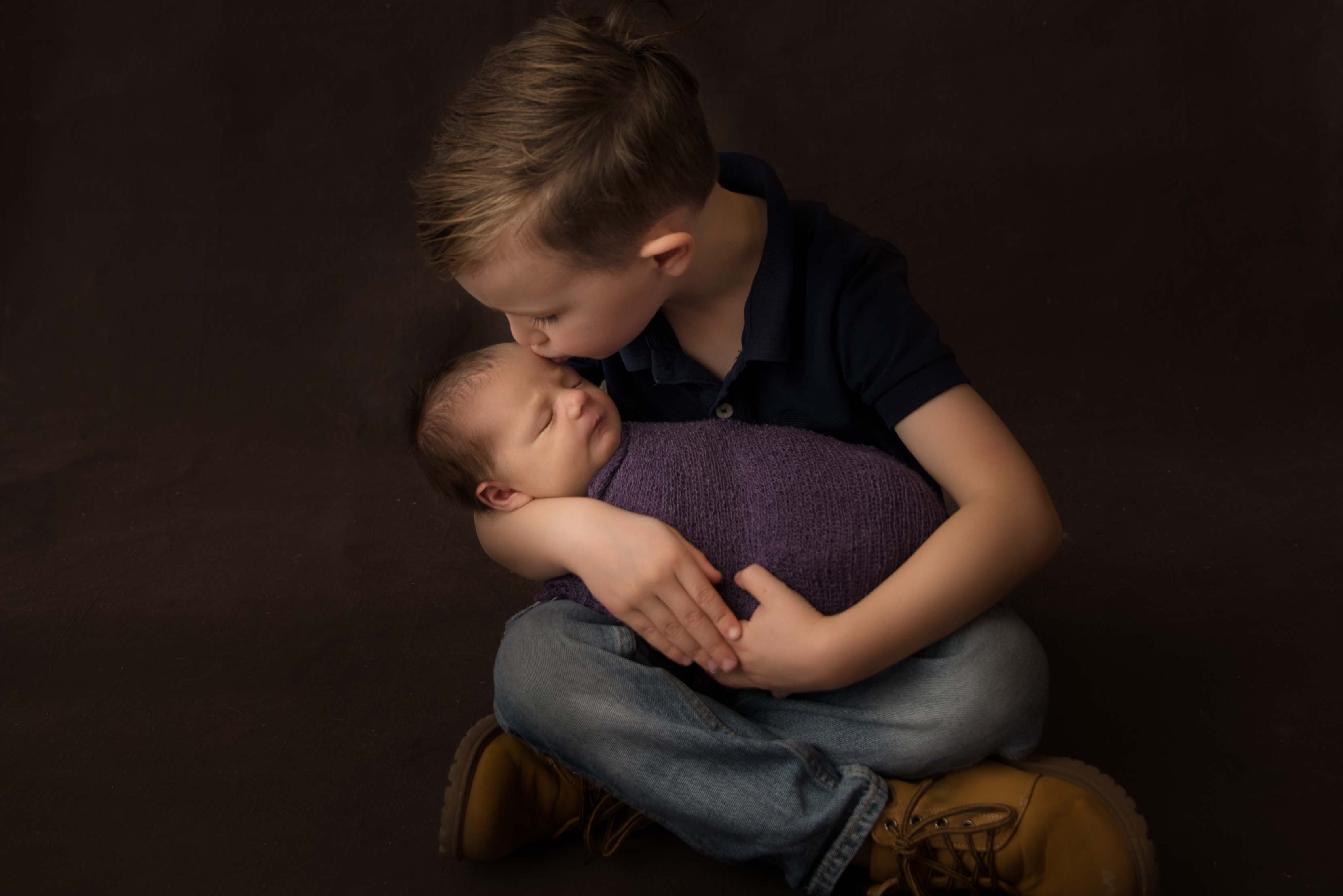 Big brother kissing his new baby sister for newborn photo.