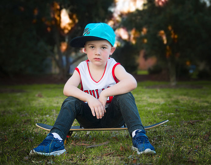 Boy sitting on skateboard for photography