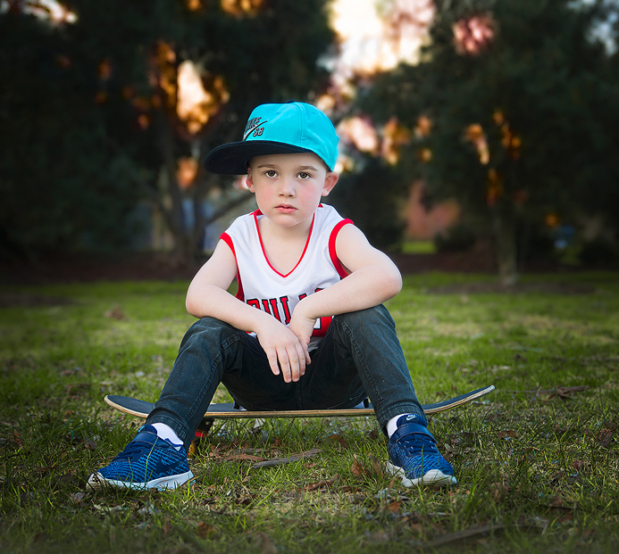 Boy sitting on skateboard for photography