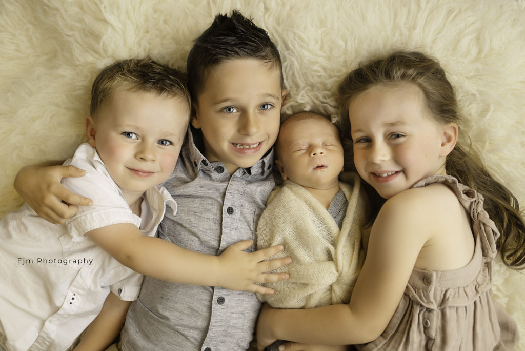 4 siblings posing for newborn photo shoot