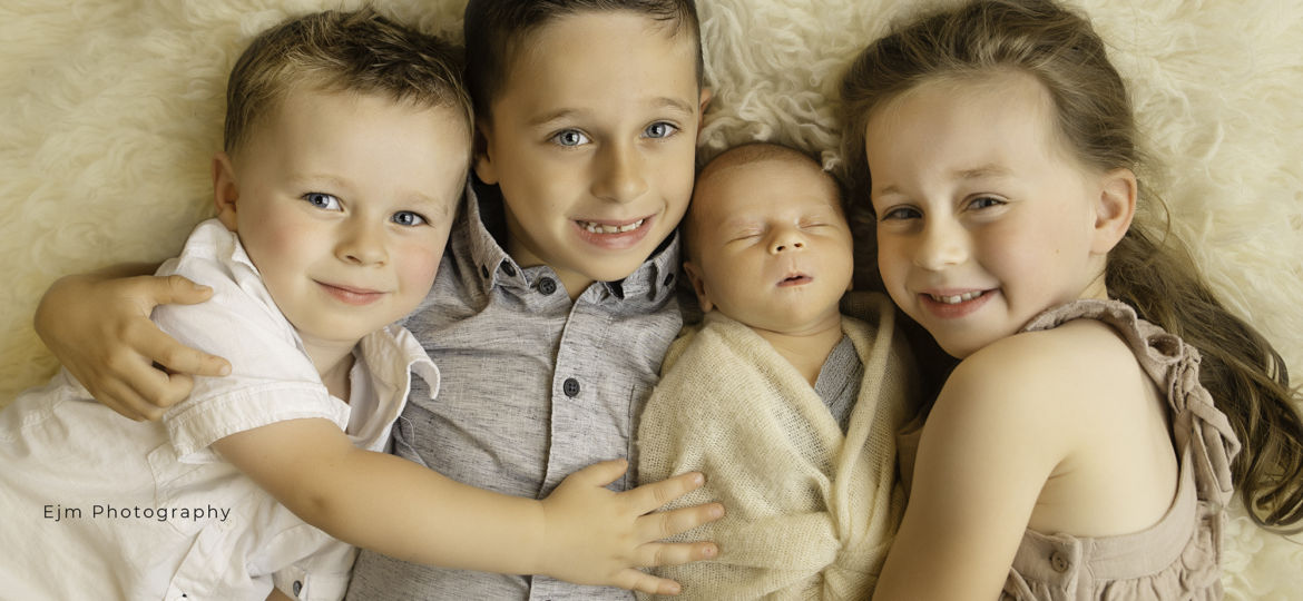 4 siblings posing for newborn photo shoot