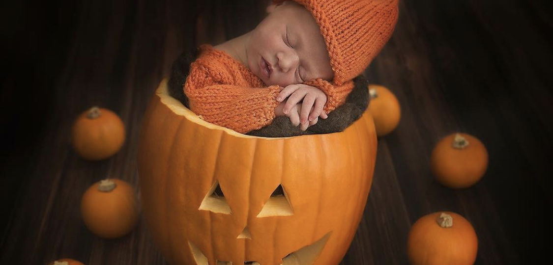 Newborn baby in pumpkin for Halloween